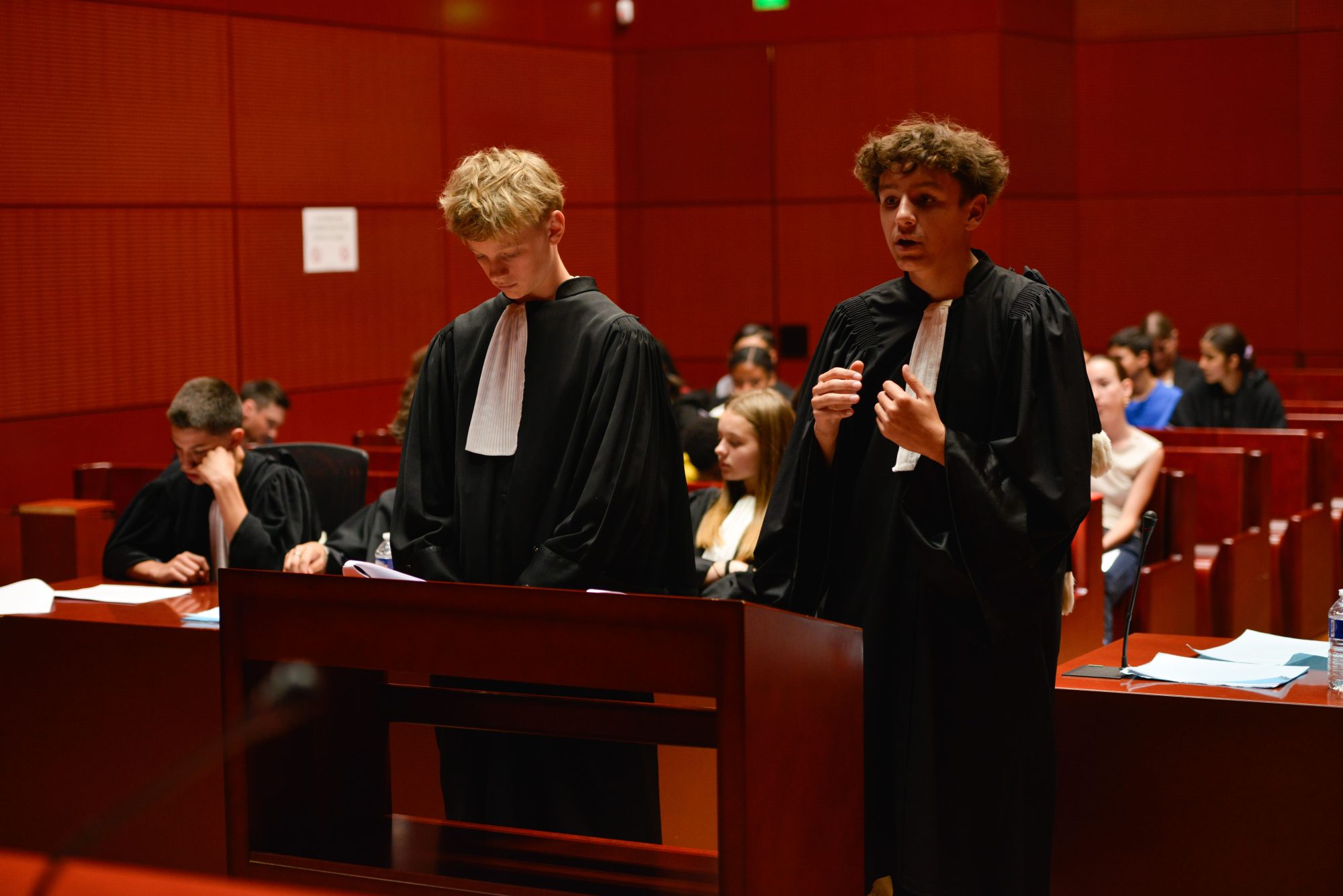 Photo de deux collégiens en tenue d'avocat dans un tribunal à Nantes, rejouant un procès fictif avec l'association Ose ton Futur